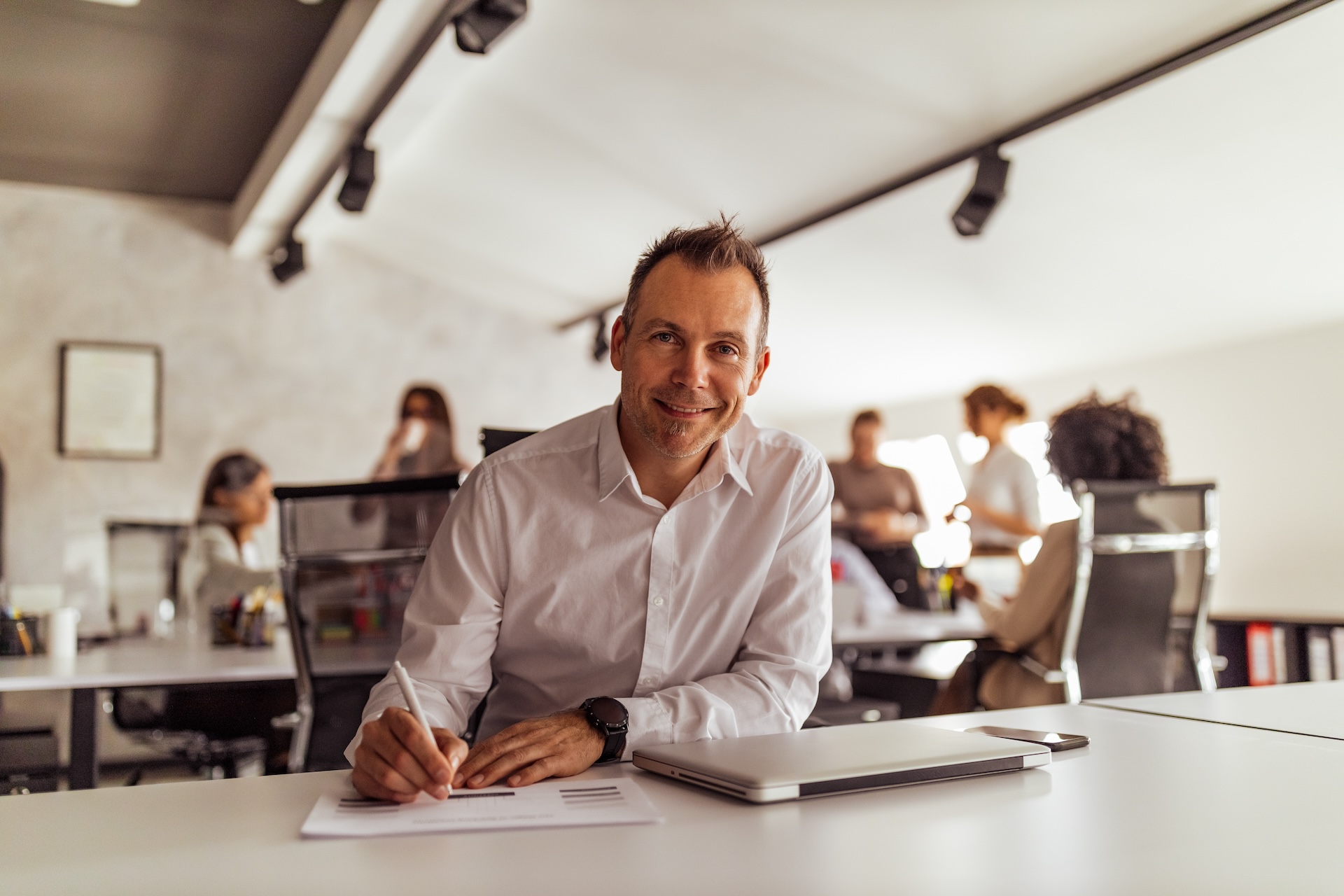 smiling business professional writing at desk in m 2025 12 19 19 07 48 utc